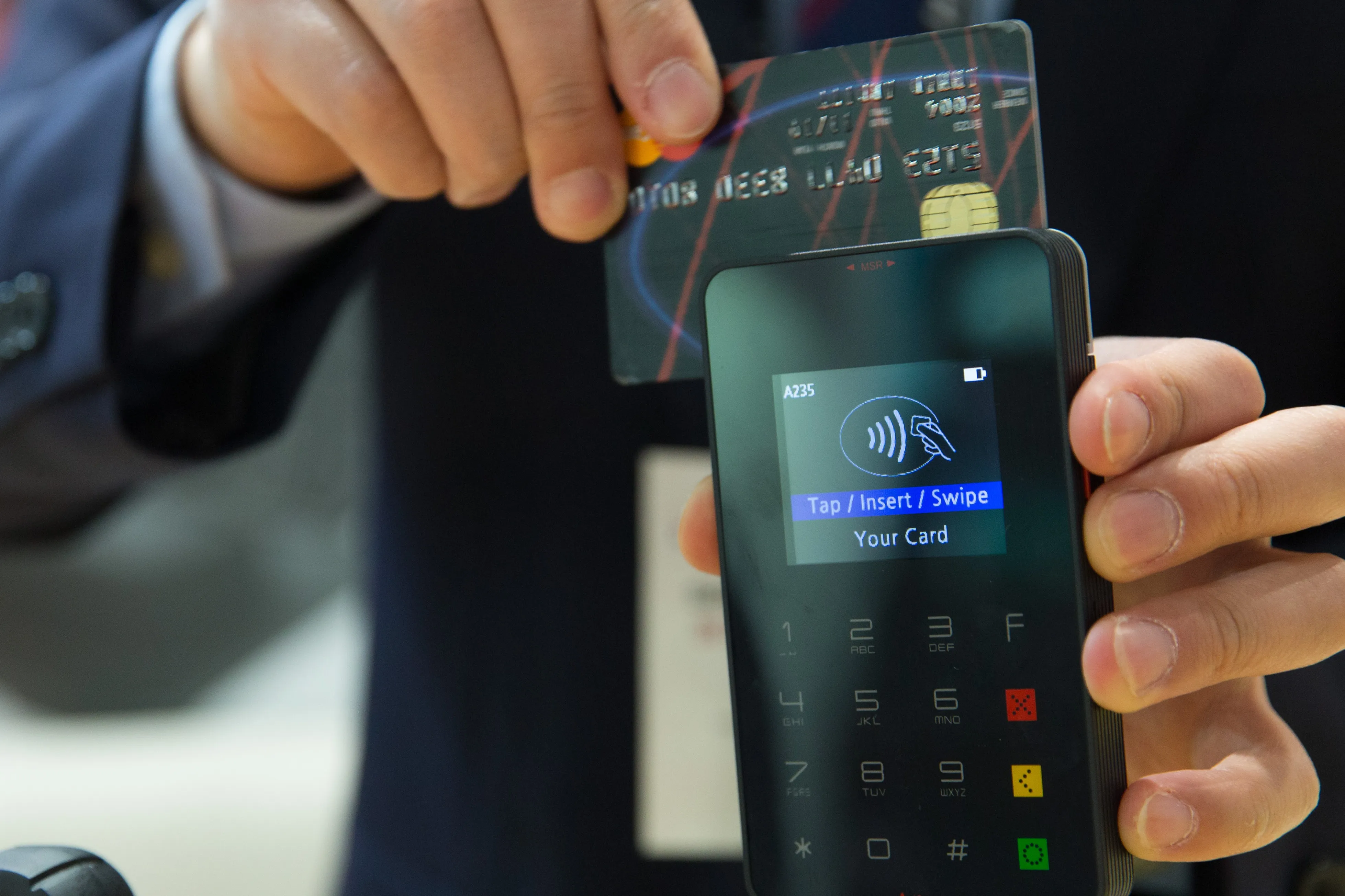 Handheld payment terminal processing a card transaction at a retail checkout